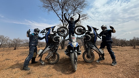 Het herenteam uit de BeNeLux-landen vormt een piramide met een coureur die in het midden op zijn motor staat en de handen omhoog steekt, terwijl de andere twee coureurs hun motoren op het achterwiel hebben neergezet en de duim opsteken.