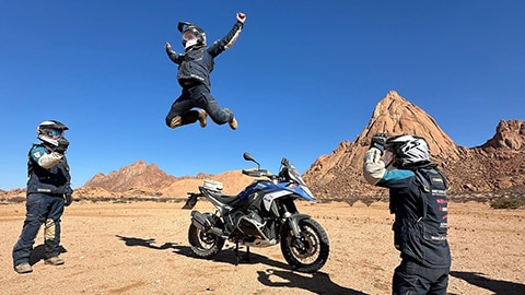Het Italiaanse herenteam tijdens hun fotochallenge. Een coureur springt van zijn R 1300 GS omhoog.