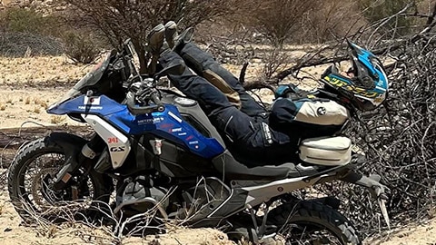 Een motorrijdster van het Japanse damesteam ligt op haar R 1300 GS. Haar benen wijzen richting stuur, terwijl de schouders en het hoofd boven de achterkant van de motor uitsteken.
