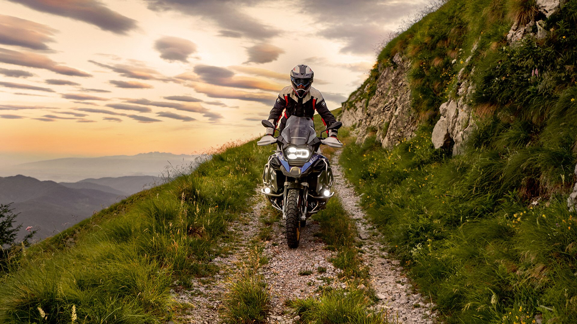 Scène de conduite avec la BMW R 1250 GS Adventure en montagne sur un chemin de terre