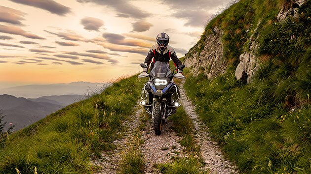 Scène de conduite avec la BMW R 1250 GS Adventure en montagne sur un chemin de terre